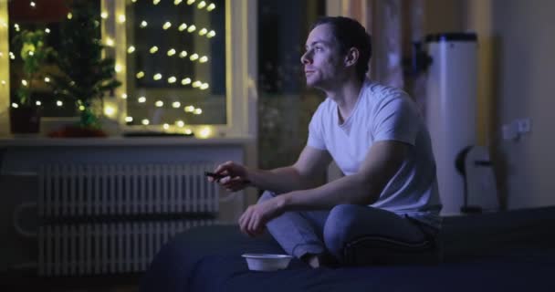 Sám doma, muž se dívá na televizi a v noci jí ořechy — Stock video