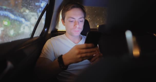 Hombre masticando chicle en un coche usando el teléfono — Vídeos de Stock