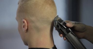 Erkek berber müşterisinin saçını kesiyor.