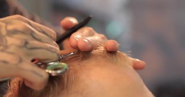 Berber berber dükkanında bir saç makasıyla kesiyor.