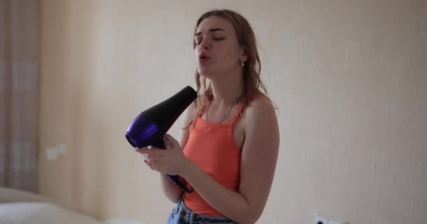 Ung kvinna torkar hår hemma och sjunger sång — Stockvideo