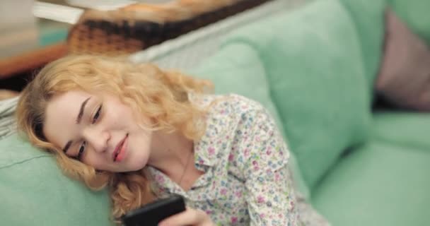 Coquette vrouw met smartphone zittend op groene bank — Stockvideo