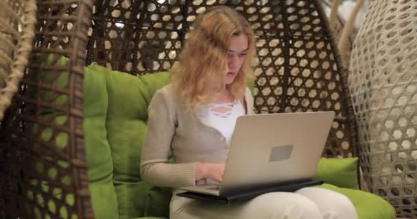 Woman working by laptop sitting in a cocoon chair — Stock Video