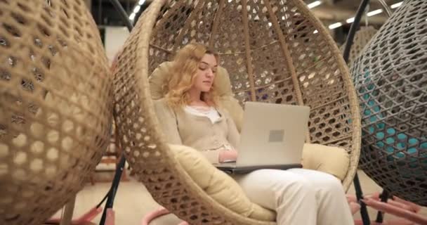 Žena pracující u laptopu sedící v kokonovém křesle — Stock video