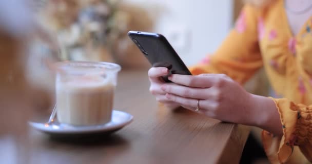 Kvinnliga händer med hjälp av smarttelefon sittande på ett café — Stockvideo