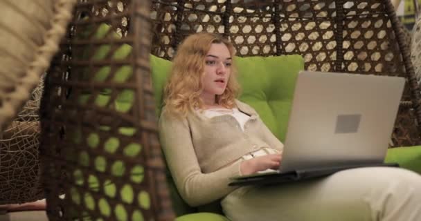 Frau arbeitet am Laptop und sitzt im Kokon-Stuhl — Stockvideo