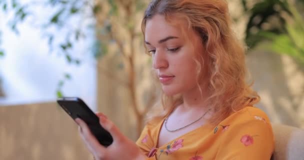 Pretty woman using smart phone sitting in a cafe — Stock Video
