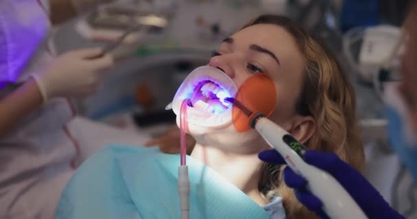 Ortodoncista fija un aparato ortopédico a los dientes de los pacientes — Vídeo de stock