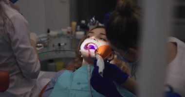 Ortodontist hastaların dişlerine diş teli takıyor.