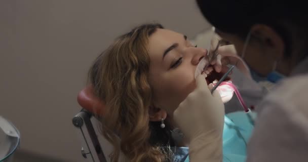 Ortodoncista fija un aparato ortopédico a los dientes de los pacientes — Vídeos de Stock