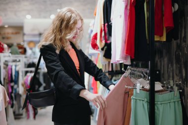 Kadın mağazadan kıyafet seçiyor.