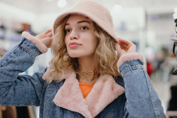 Pretty woman trying on a hat in the store