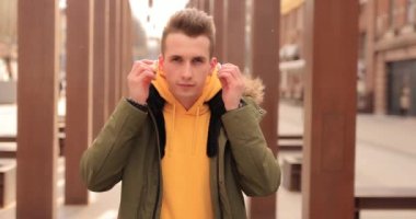 Stylish man puts on wireless earbuds into his ears