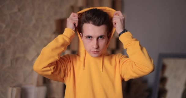 Man in yellow hoodie puts on hood at home, slow motion 4k at 120fps — Stok video