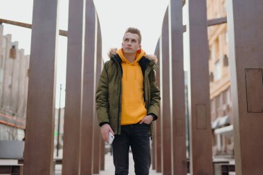 Yakışıklı bir adam, kulaklıklarında kablosuz kulaklıklarla bir kış şehrinde yürüyor.