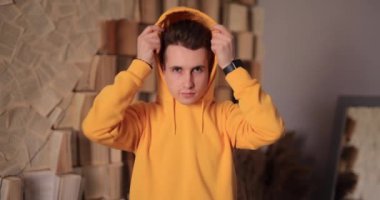 Man in yellow hoodie puts on hood at home, slow motion 4k at 120fps