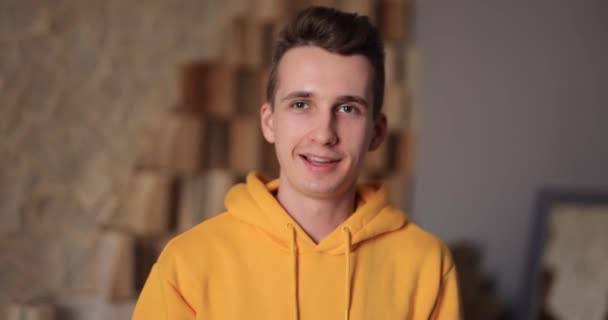 Fiatal, mosolygós férfi sárga kapucnis portréval otthon — Stock videók