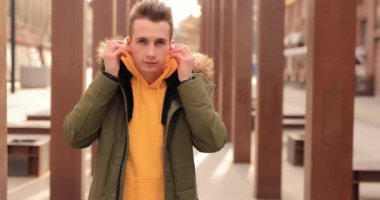 Stylish man puts on wireless earbuds into his ears