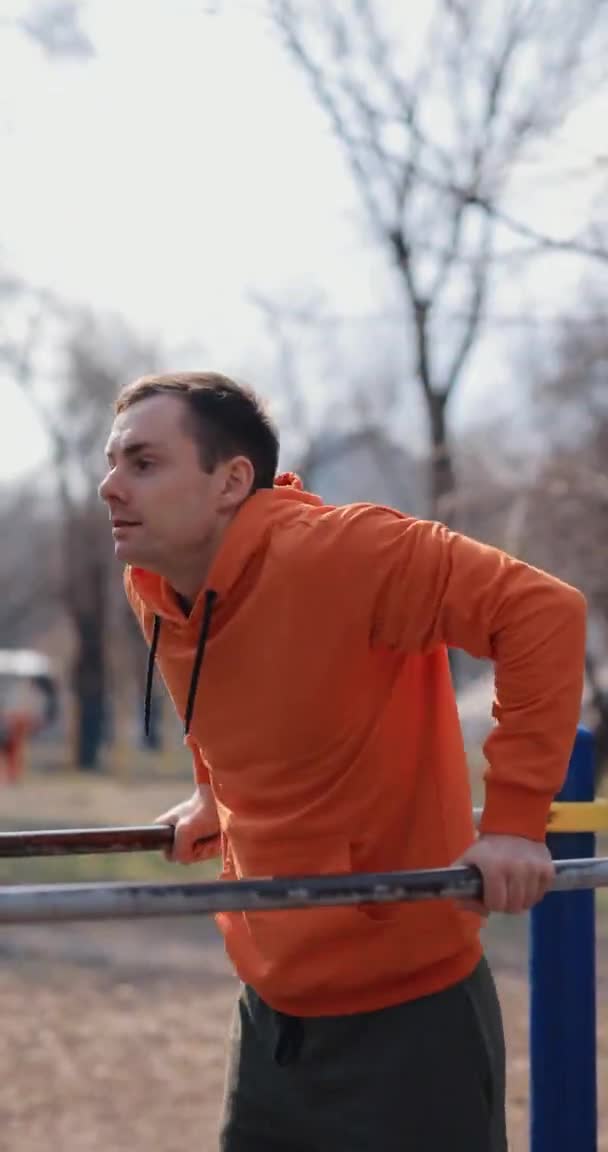 Man push ups on horizontal bars outdoor, vertical video — Stock Video