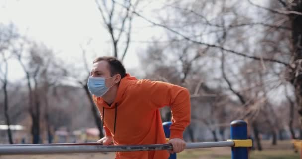 Άντρας push ups σε οριζόντιες μπάρες εξωτερική με χειρουργική μάσκα — Αρχείο Βίντεο