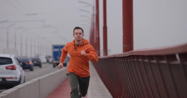 Férfi narancssárga kapucnis futás gyorsan a hídon, lassított felvétel — Stock videók