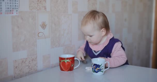 Carino bambina gioca con le tazze al tavolo della cucina — Video Stock