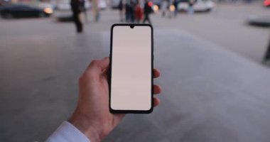 Akıllı telefon modeli taşıyan bir erkek, şehrin sol dokunmatik ekranında yürüyor.