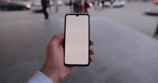 Мужская рука с макетом смартфона ходит по городскому краю с сенсорным экраном слева — стоковое видео
