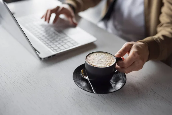 Dizüstü bilgisayarda çalışan yakın erkek eller bir fincan latte alın. — Stok fotoğraf