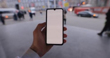 Şehrin sol dokunmatik ekranında akıllı telefon modeli tutan bir erkek.