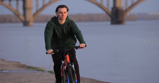 Bicyclist riding bike at river embankment, slow motion — Stock Video