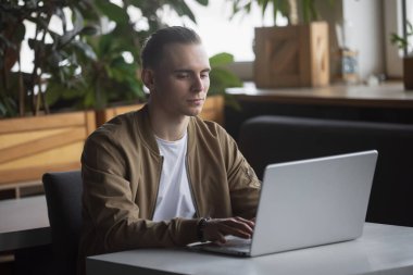 Bir kafede bilgisayar başında çalışan serbest çalışan bir adam.