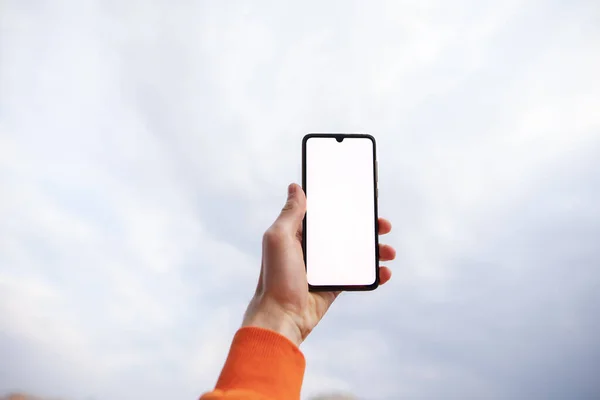 Mockup de mano masculina sosteniendo teléfono inteligente contra el cielo, búsqueda en red — Foto de Stock