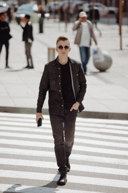 Genç, modaya uygun bir adam şehirde bir zebrayla karşıdan karşıya geçiyor.