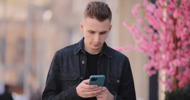 UCRÂNIA, DNEPR - 22 de abril de 2021: Jovem usando o IPhone 11 pro max em uma cidade da primavera — Vídeo de Stock