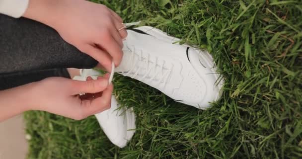 Primeros planos mujer atando cordones de zapatos en una hierba, vídeo vertical — Vídeo de stock