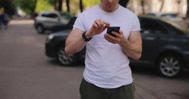 Bir yaz şehrinde cep telefonu kullanan kırpılmış bir adam.