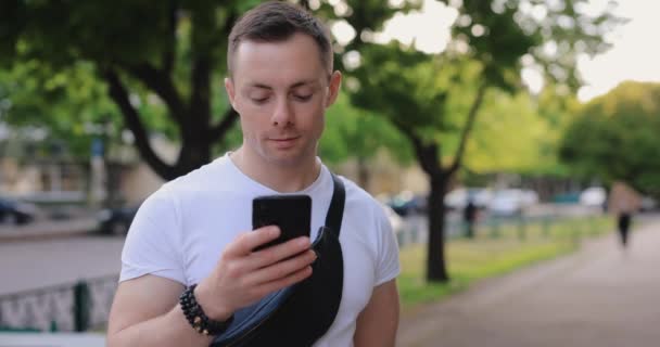 Cámara lenta hombre caucásico sonriendo mirando en el teléfono inteligente, espacio de copia — Vídeos de Stock