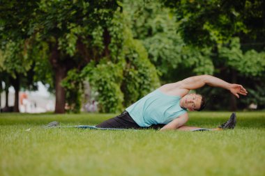 Adam parkta yoga egzersizi yapıyor.