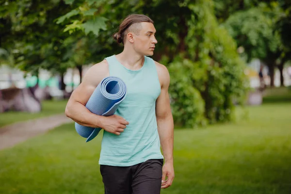 Yoga man going with mat in a park — Stock Photo, Image