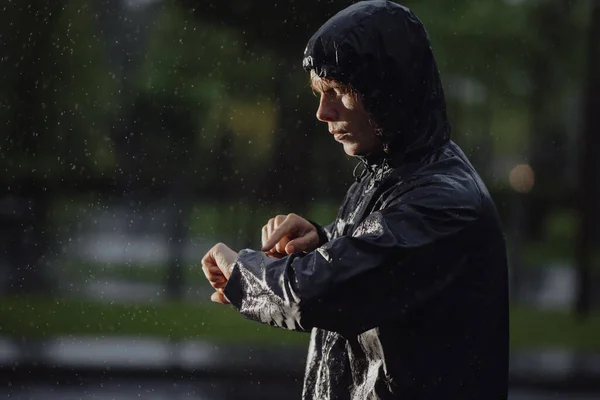 Koşucu, yağmurun altında saatine bakar. — Stok fotoğraf