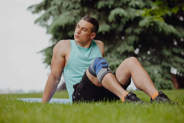 Sport man zittend op gras in een park — Stockfoto