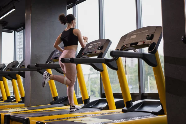 Mulher fitness corre em uma esteira — Fotografia de Stock