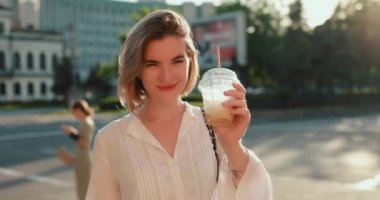 Şehirde soğuk bir latte içen mutlu kadın.