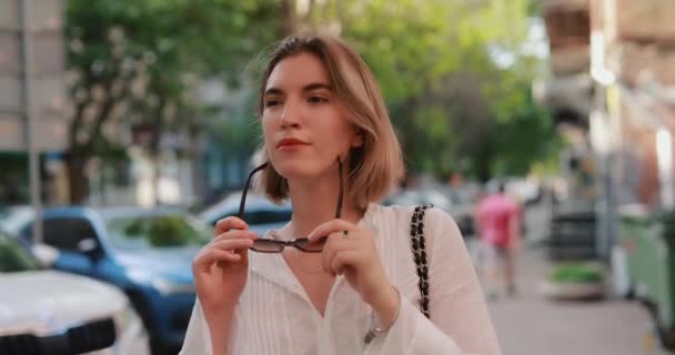 Femme portant des lunettes de soleil marchant par la rue de la ville — Video