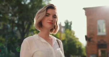 Bir yaz şehrinde kadın ağır çekimde kablosuz kulaklık takıyor.