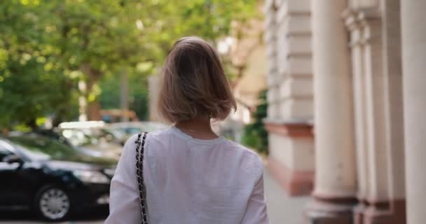 Femme marche dans la ville tourner en arrière regarde la caméra — Video