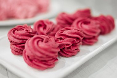 Tabakta bir sürü kırmızı ve pembe marşmelov var.