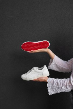 Siyah arka planda kırmızı tabanlı beyaz spor ayakkabılar.