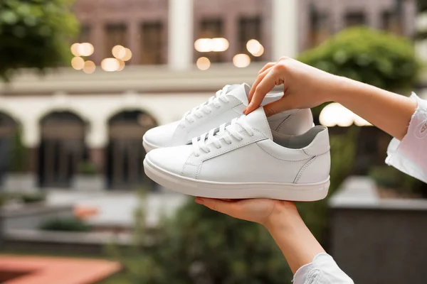 Nuevas zapatillas blancas en manos femeninas — Foto de Stock